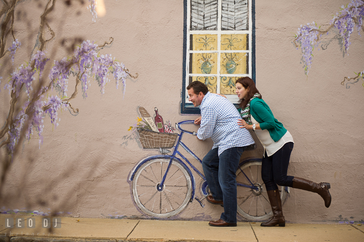 Engaged couple pretending to ride a painting bicycle. Annapolis Eastern Shore Maryland pre-wedding engagement photo session at downtown, by wedding photographers of Leo Dj Photography. http://leodjphoto.com