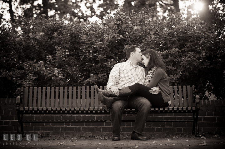 Engaged guy kissed his fiancée who is sitting on his lap. Annapolis Eastern Shore Maryland pre-wedding engagement photo session at downtown, by wedding photographers of Leo Dj Photography. http://leodjphoto.com