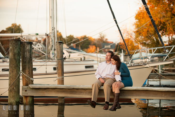 Engaged couple cuddling on a boat dock at Eastport with fall foliage in the background. Annapolis Eastern Shore Maryland pre-wedding engagement photo session at downtown, by wedding photographers of Leo Dj Photography. http://leodjphoto.com