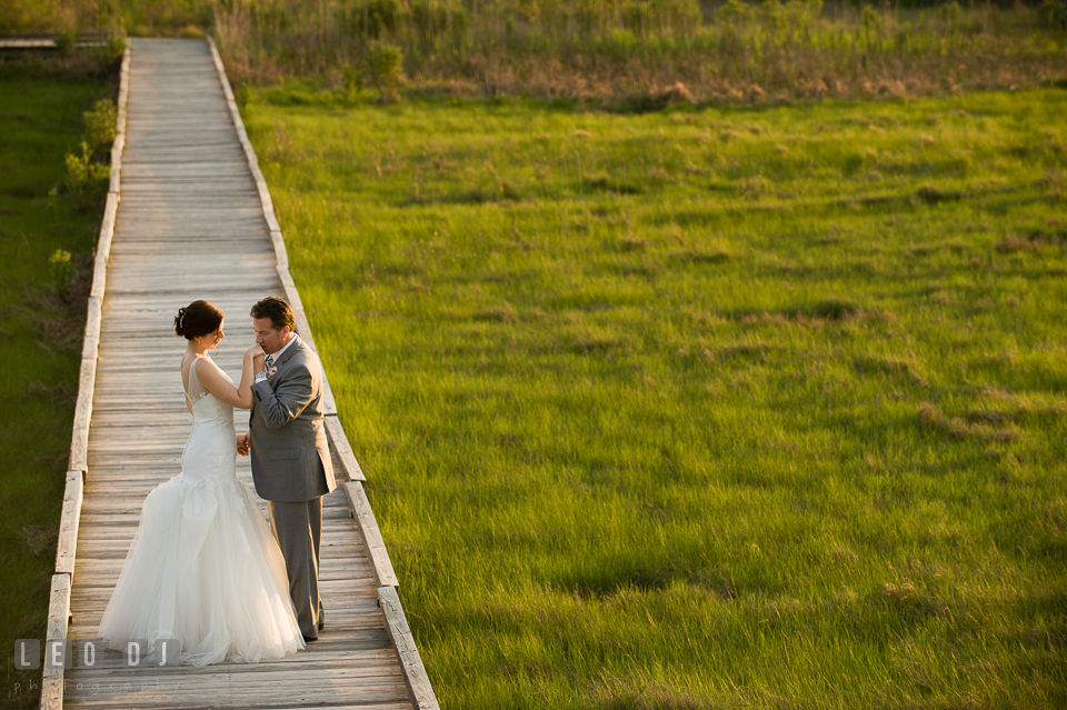 Groom kissing Bride's hand on the boardwalk at the beach. Chesapeake Bay Environmental Center, Eastern Shore Maryland, wedding reception and ceremony photo, by wedding photographers of Leo Dj Photography. http://leodjphoto.com