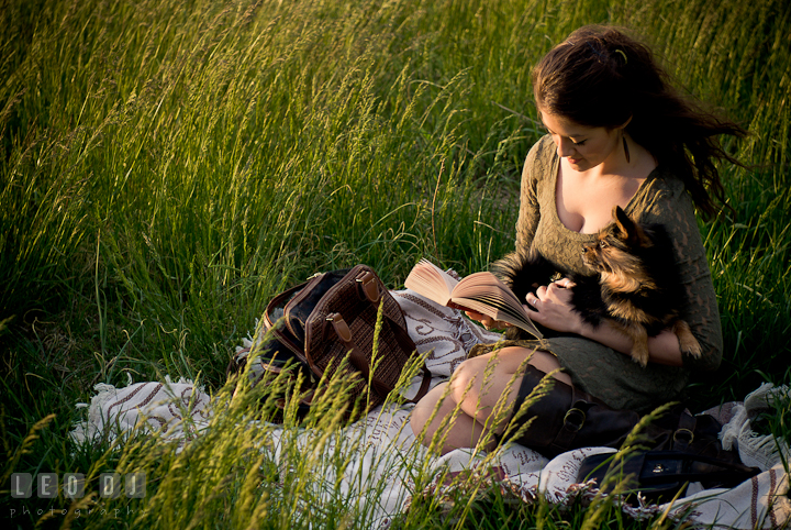 Girl in a grass meadow reading her book accompanied by her pet dog. Eastern Shore, Maryland, Kent Island High School senior portrait session by photographer Leo Dj Photography. http://leodjphoto.com