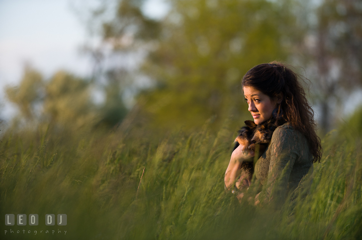 Girl in a grass field holding her pet dog looking at the sunset. Eastern Shore, Maryland, Kent Island High School senior portrait session by photographer Leo Dj Photography. http://leodjphoto.com