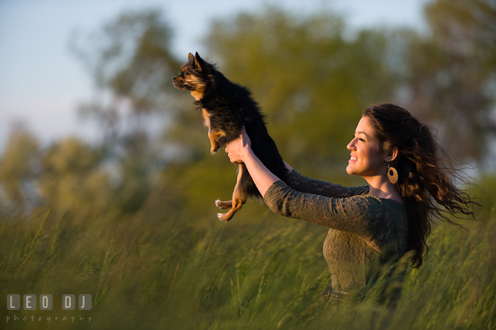 Girl in a grass meadow holding up her pet dog high up in the air. Eastern Shore, Maryland, Kent Island High School senior portrait session by photographer Leo Dj Photography. http://leodjphoto.com