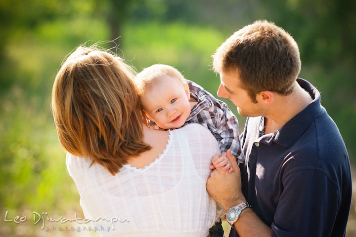 Mother holding baby over her shoulder. Father holding baby's hand. Eastern Shore Maryland Kent Island Family Lifestyle Portrait Photo Session by Photographer Leo Dj Photography