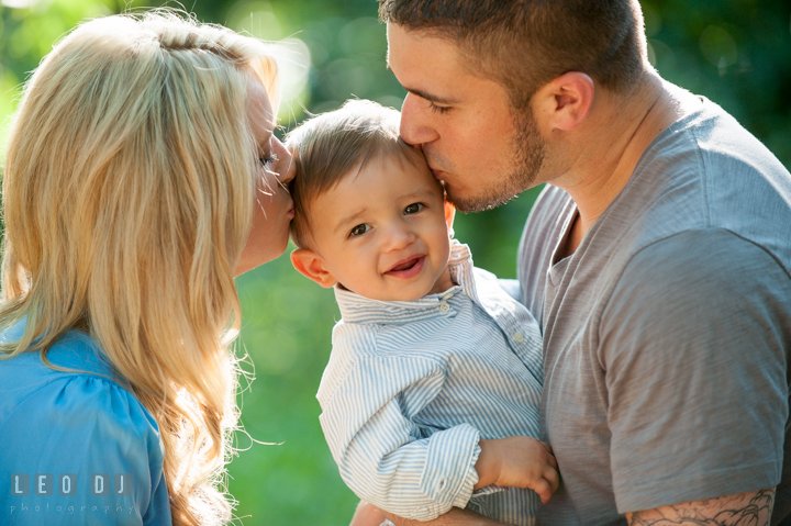 Mom and Dad kissing their little son. Kent Island, Annapolis, Eastern Shore Maryland candid children and family lifestyle portrait photo session by photographers of Leo Dj Photography. http://leodjphoto.com