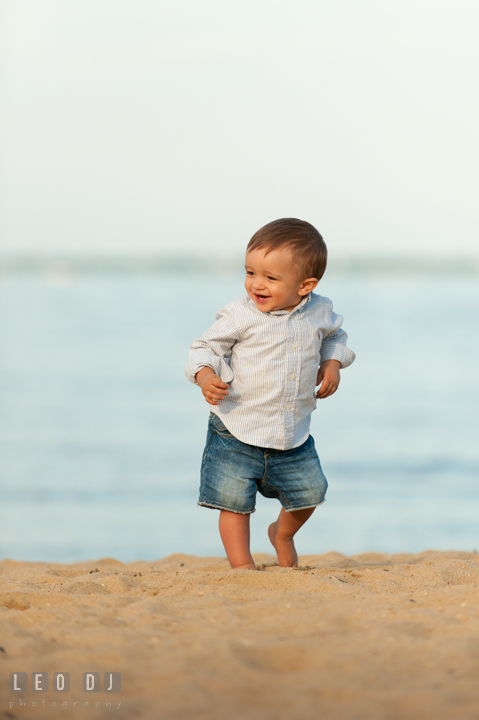 Little toddler boy walking on the beach and smiling. Kent Island, Annapolis, Eastern Shore Maryland candid children and family lifestyle portrait photo session by photographers of Leo Dj Photography. http://leodjphoto.com