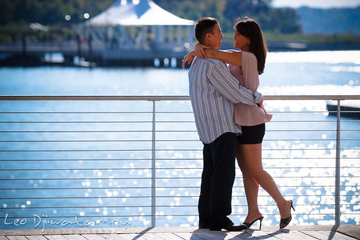 Engaged couple hugging with reflective water in the background. National Harbor, Gaylord National Hotel pre-wedding engagement photo session