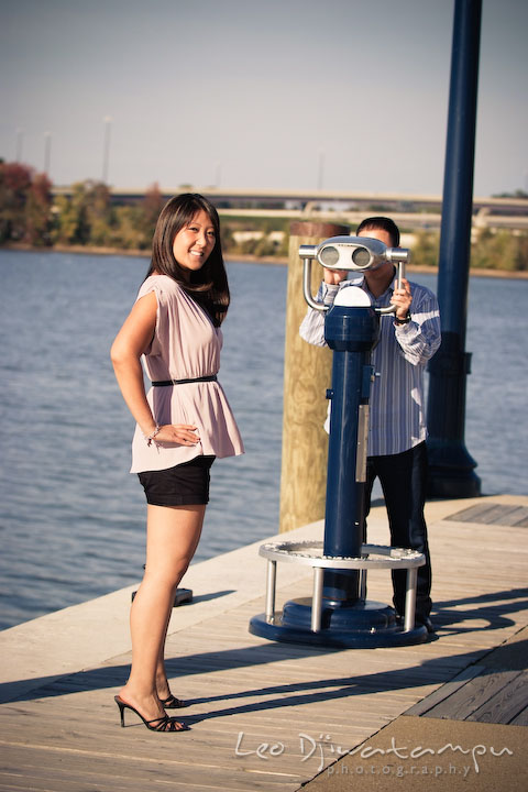 Engaged guy looking at his fiancee through a binocular. National Harbor, Gaylord National Hotel pre-wedding engagement photo session