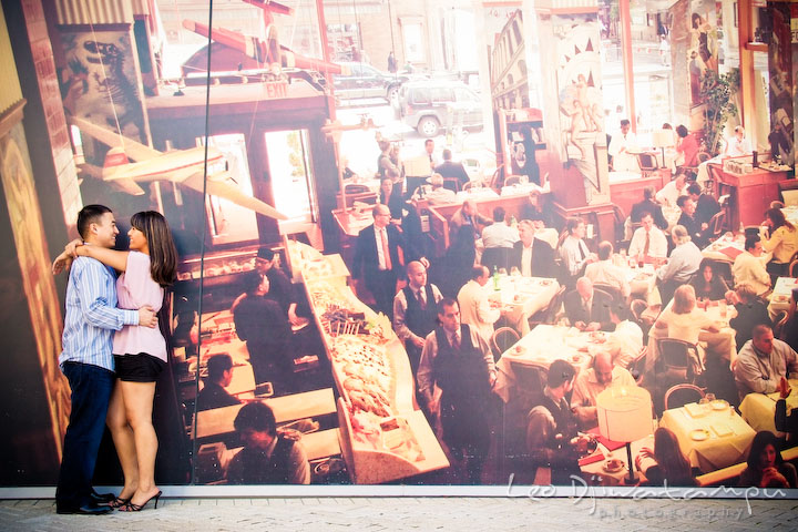 Engaged couple cuddling by a giant photo wall. National Harbor, Gaylord National Hotel pre-wedding engagement photo session