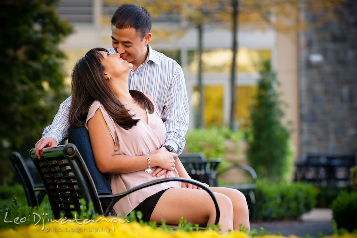 Engaged couple sitting on a bench and looking at each other. National Harbor, Gaylord National Hotel pre-wedding engagement photo session