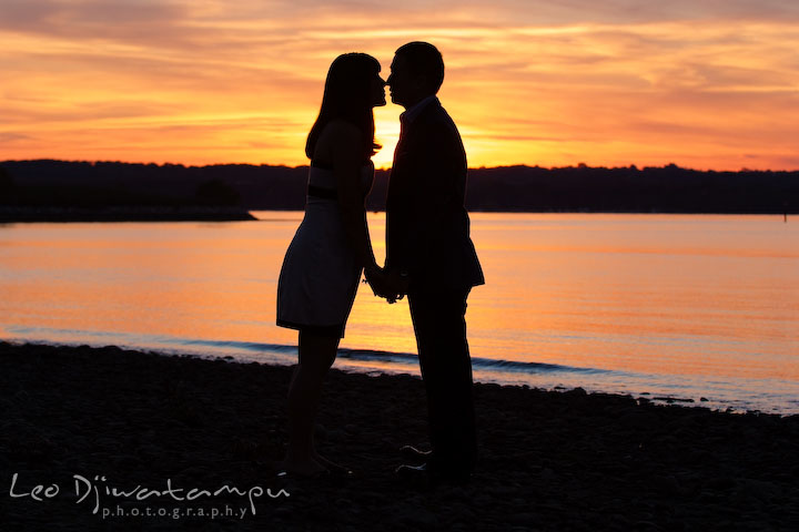 Engaged couple holding hands and almost kiss with water and sunset in the background. National Harbor, Gaylord National Hotel pre-wedding engagement photo session