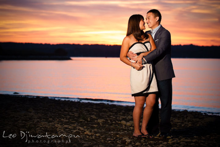 Fiancé holding his fiancée with sunset in the background. National Harbor, Gaylord National Hotel pre-wedding engagement photo session