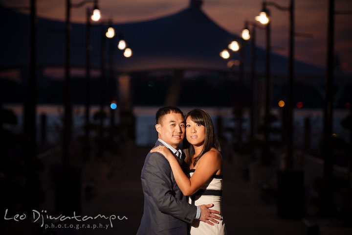 Fiancé and his fiancée holding each other by the pier after sunset. National Harbor, Gaylord National Hotel pre-wedding engagement photo session