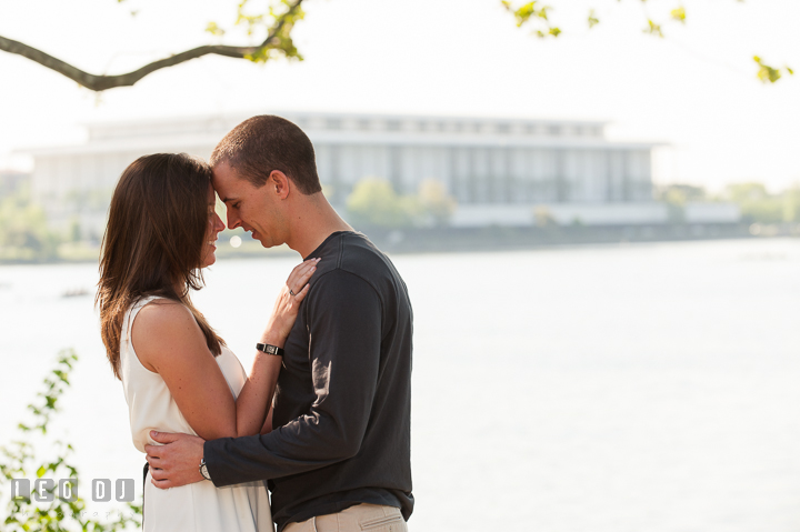 Engaged girl cuddling with her fiancé in front of The Kennedy Center. Georgetown Washington DC pre-wedding engagement photo session, by wedding photographers of Leo Dj Photography. http://leodjphoto.com