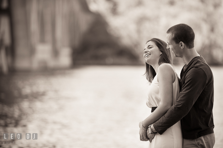 Engaged couple cuddling and laughing together by the Potomac Riverfiancée. Georgetown Washington DC pre-wedding engagement photo session, by wedding photographers of Leo Dj Photography. http://leodjphoto.com