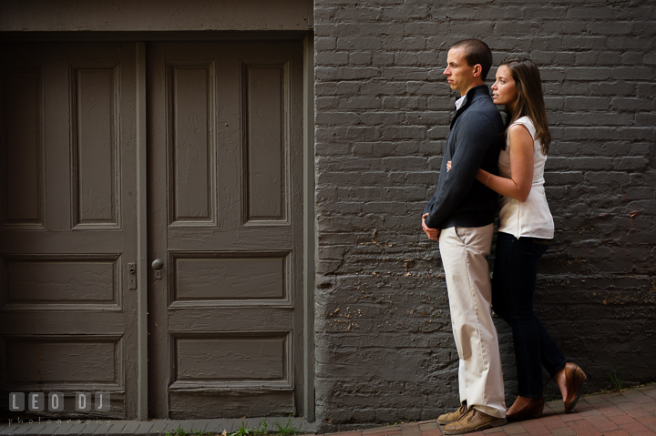 Engaged guy hugged by his fiancée by green doors in an alley. Georgetown Washington DC pre-wedding engagement photo session, by wedding photographers of Leo Dj Photography. http://leodjphoto.com