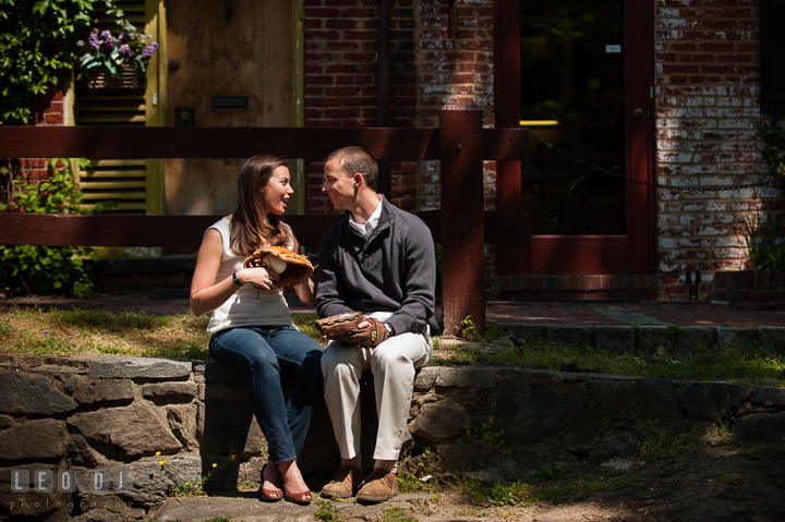 Engaged couple sitting by the homes at C&O Canal holding baseball gloves. Georgetown Washington DC pre-wedding engagement photo session, by wedding photographers of Leo Dj Photography. http://leodjphoto.com