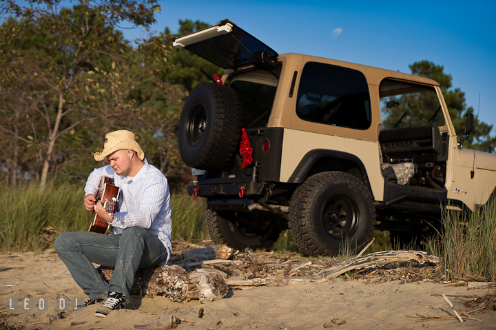 Guy with straw hat sitting on the beach and playing guitar by his SUV. Eastern Shore, Maryland, Kent Island High School senior portrait session by photographer Leo Dj Photography. http://leodjphoto.com