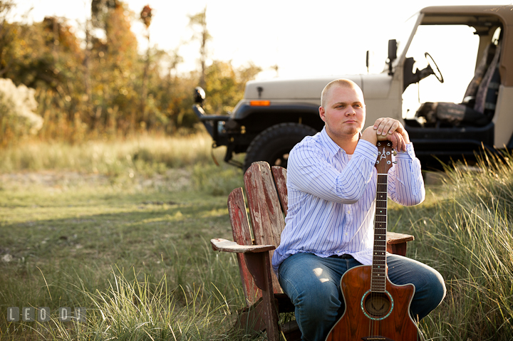 Guy sitting on adirondack chair and resting on his guitar. Eastern Shore, Maryland, Kent Island High School senior portrait session by photographer Leo Dj Photography. http://leodjphoto.com