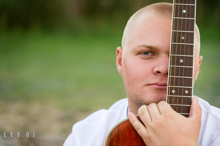 Guy holding guitar in front of face. Eastern Shore, Maryland, Kent Island High School senior portrait session by photographer Leo Dj Photography. http://leodjphoto.com